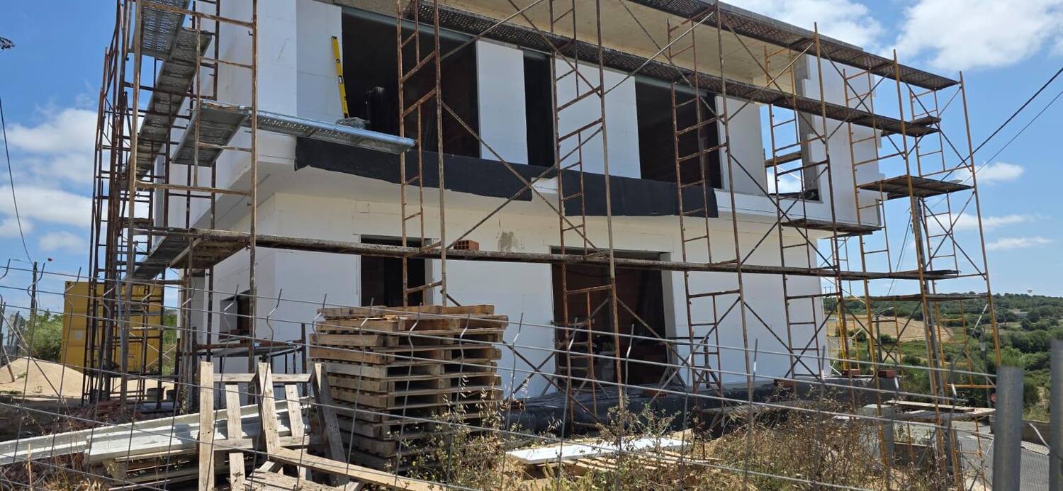 Vista lateral de moradia nova com sistema ETICS aplicado nas paredes exteriores, painéis EPS visíveis antes da barramento