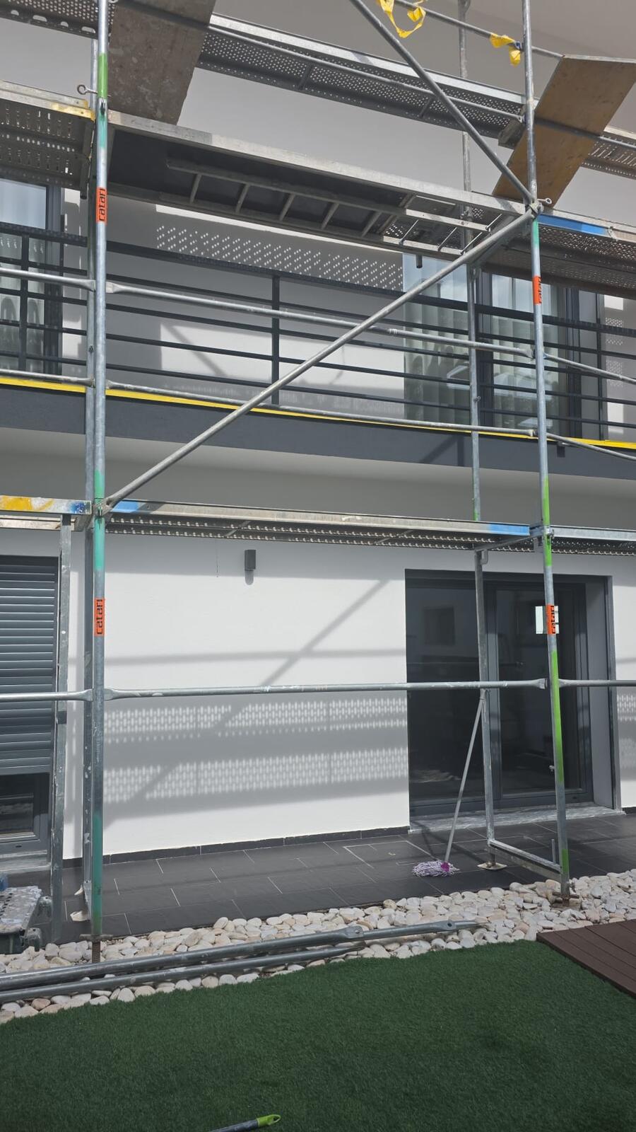 Fachada traseira de moradia com andaime montado e varandas com guarda em ferro pintado a cinza-grafite