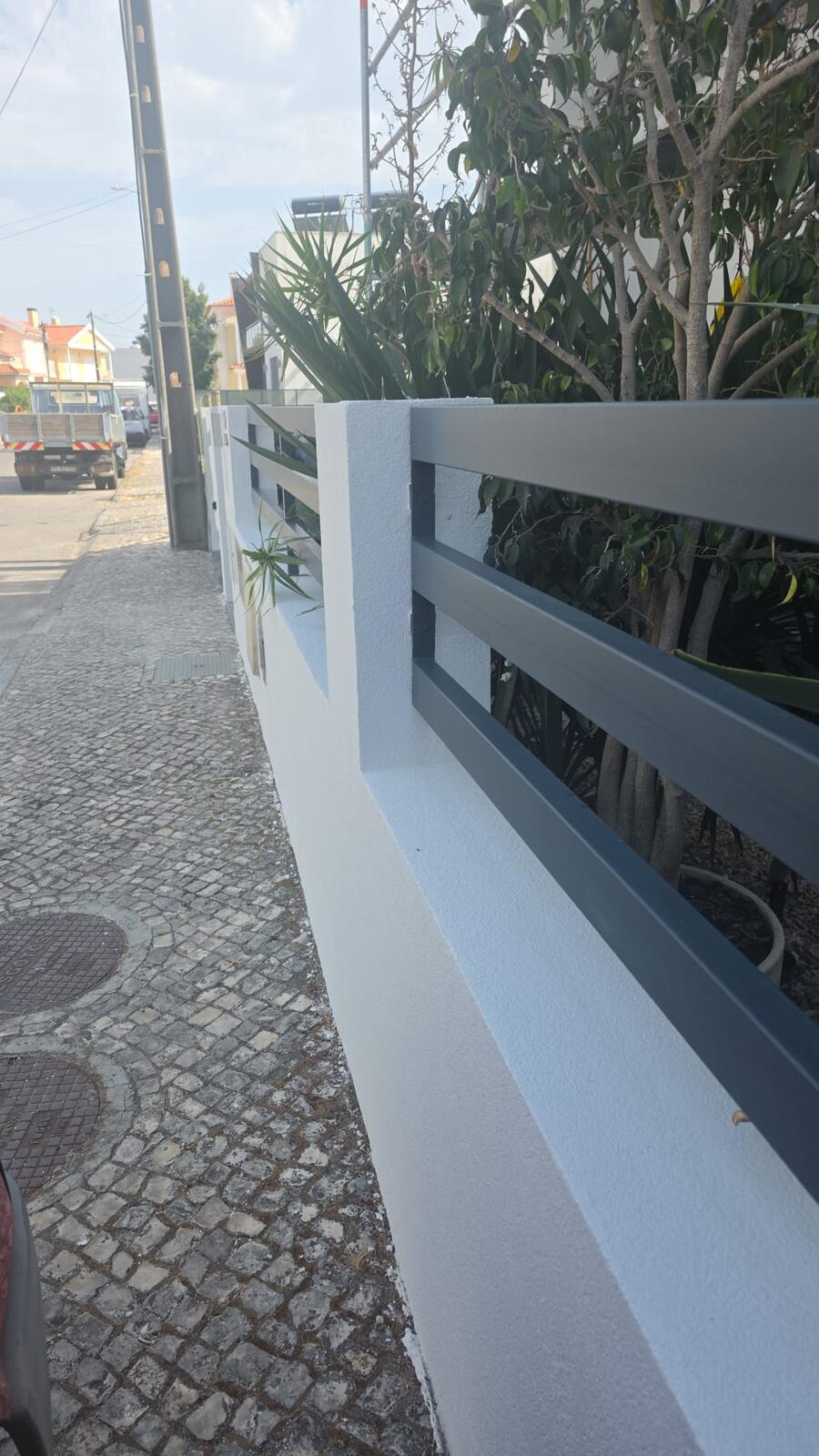 Muro exterior pintado em branco com guarda em alumínio cinza-grafite, acabamento limpo junto ao passeio